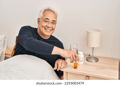 Senior man taking pills treatment sitting on bed at bedroom - Powered by Shutterstock