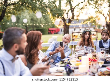 A senior man taking selfie at the wedding reception outside in the backyard. - Powered by Shutterstock