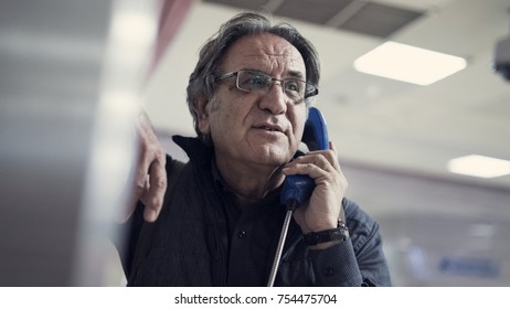 Senior Man Talking On Public Payphone