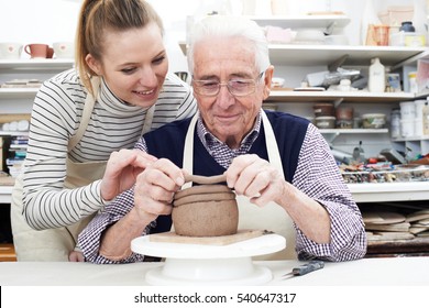 Senior Man With Teacher In Pottery Class