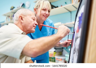 Senior Man And Therapist Are Painting Together In Creative Painting Therapy