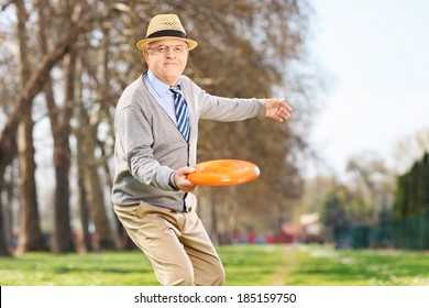 Senior Man Throwing A Frisbee Disk In A Park