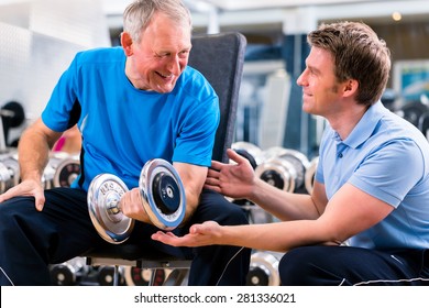 Senior Man And Trainer At Exercise In Gym With Dumbbell Weights