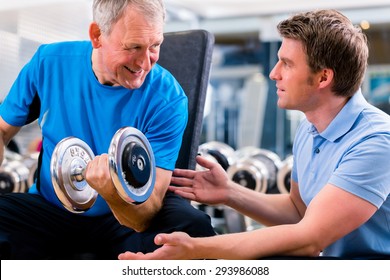 Senior man and trainer at exercise in gym with dumbbell weights