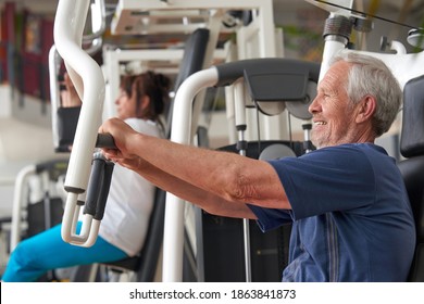 Senior man training at gym, side view. Elderly caucasian man training on machine at fitness club. Train your brain.