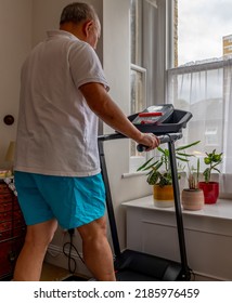 A Senior Man Trying To Keep Fit Working Out On A Treadmill At Home.