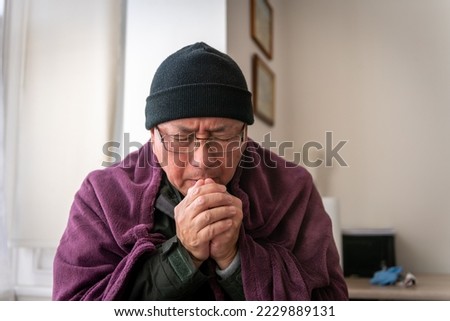 A senior man trying to keep warm indoors as household energy cost more then doubled.