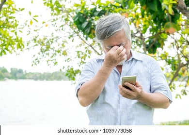 Senior man trying to use a mobile device. Very confuse old chinese man trying very hard to use his smart phone. Not happy as he struggle.