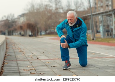 The senior man use hands hold on his knee while running outdoor