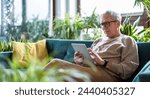 Senior man using digital tablet while sitting on sofa in living room at home
