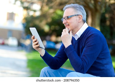 Senior man using a digital tablet outdoor in the park