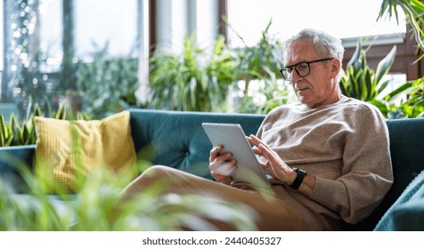 Senior man using digital tablet while sitting on sofa in living room at home
 - Powered by Shutterstock