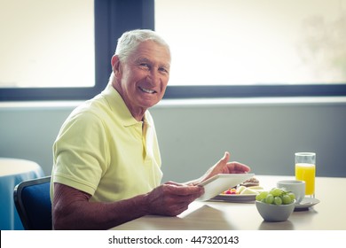 Senior man using digital tablet while having breakfast