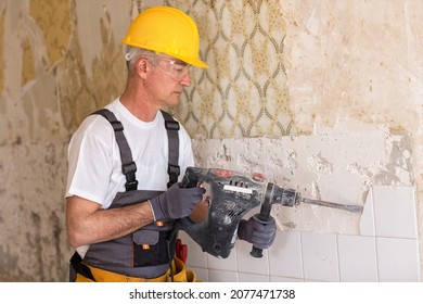 Senior Man Using Drill At Contruction Site