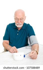 Senior Man Using A Home Blood Pressure Machine To Check His Vital Statistics.  White Background.