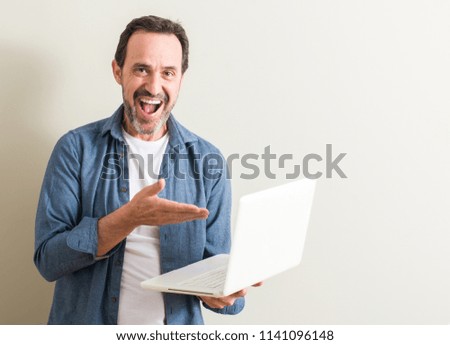 Senior man using laptop computer very happy pointing with hand and finger