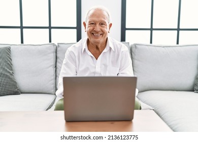 Senior Man Using Laptop At Home Sitting On The Sofa With A Happy And Cool Smile On Face. Lucky Person. 
