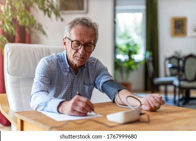 Senior man using medical device to measure blood pressure
