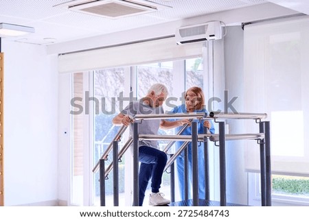 Senior man using parallel bars with physiotherapist assistance for mobility training in rehab center. This image can be used for commercial purposes related to healthcare rehabilitation and senior care.