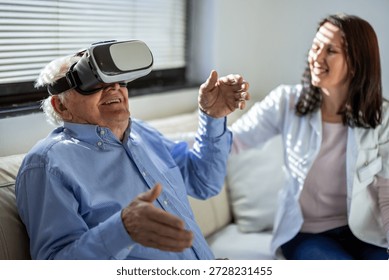 Senior man using virtual reality headset with nurse in background at nursing home - Powered by Shutterstock - Get 15% off with code: PIKWIZARD15