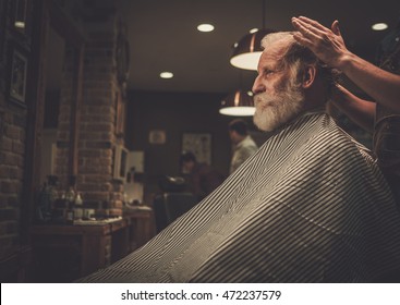 Senior man visiting hairstylist in barber shop.