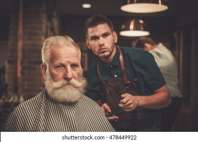 Senior Man Visiting Hairstylist In Barber Shop.