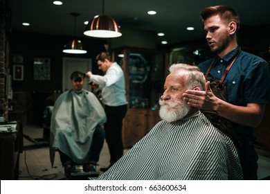 Senior Man Visiting Hairstylist In Barber Shop.