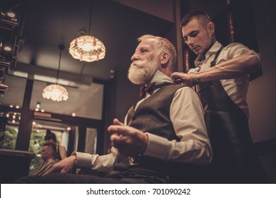 Senior Man Visiting Hairstylist In Barber Shop.