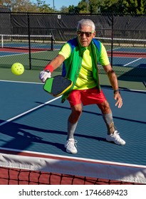 Senior Man Volleys A Pickleball Over The Net