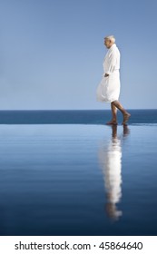 Senior Man Walking By A Pool With Bathrobe