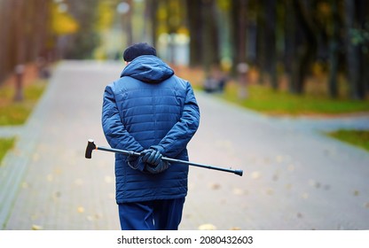 Senior Man With Walking Cane In Hand Behind His Back Alone. Old Man With Cane Enjoy Walk In City Park. Senior Man Walk Alone.