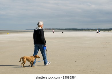 Senior Man Is Walking His Dog At The Beach