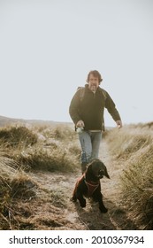 Senior Man Walking His Dog On A Coastal Trail