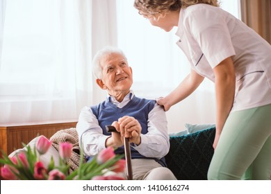 Senior Man With A Walking Stick Being Comforted By Nurse In The Hospice