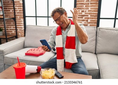 Senior Man Watching Football Looking At Smartphone Celebrating Victory With Happy Smile And Winner Expression With Raised Hands 