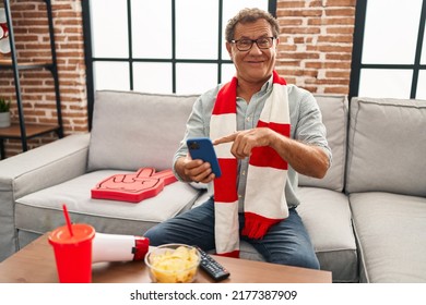 Senior Man Watching Football Looking At Smartphone Smiling Happy Pointing With Hand And Finger 