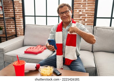 Senior Man Watching Football Looking At Smartphone Pointing Finger To One Self Smiling Happy And Proud 