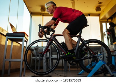 Senior man watching online motivation video and cycling bike during home workout