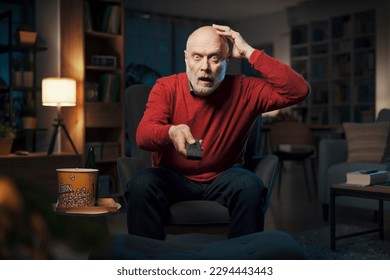 Senior man watching TV late at night, he is watching a scary horror movie - Powered by Shutterstock