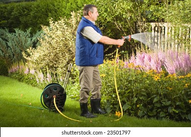 Senior Man Watering Flowers In The Garden