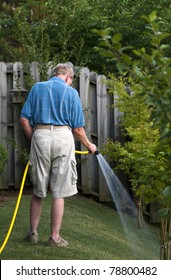 A Senior Man Watering The Lawn.