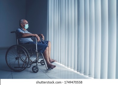 Senior man wearing a face mask and sitting on the wheelchair near the window during coronavirus outbreak in the hospital - Powered by Shutterstock