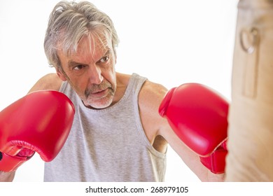 Senior Man Wearing Gloves Using A Punching Bag 