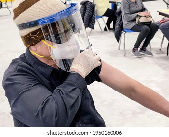 Senior Man Wearing N95 Mask And Face Shield Exposing Arm And Getting Ready For His Covid-19 Vaccine Shot At Government Vaccination Site. Canada And US Rapidly Accelerate Vaccine Rollout To Public.