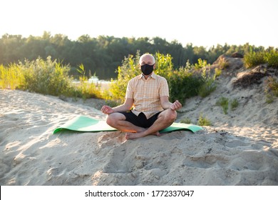 Senior Man Wearing Protective Mask Sitting In Nature, Doing Yoga Exercise.