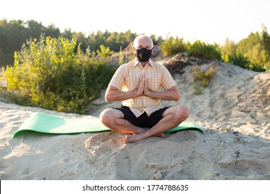 Senior Man Wearing Protective Mask Meditating Sitting In Nature, Doing Yoga Exercise.