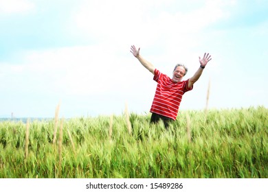 Senior Man Wearing A Red Shirt Happy In The Middle Of A Wheat Field In Canada