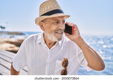 Senior man wearing summer hat talking on the smartphone at seaside - Powered by Shutterstock