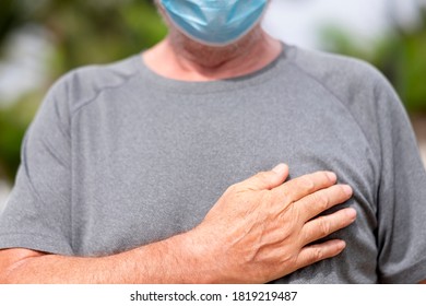 Senior Man Wearing Surgical Mask Greets With His Hand Over The Heart. The New Greeting Recommended By The OMS World Health Organisation Due To The Coronavirus Covid-19 Pandemic