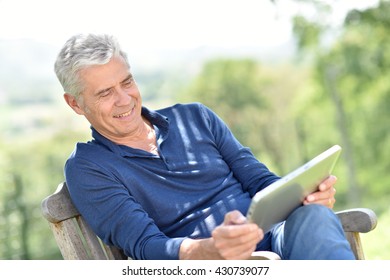 Senior Man Websurfing On Tablet Outside